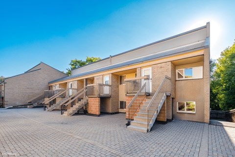 A sunny day at a brick building with a staircase leading to the entrance.