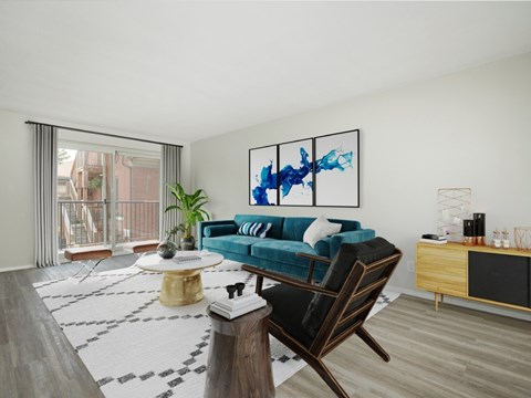A living room with a blue couch and a painting on the wall.