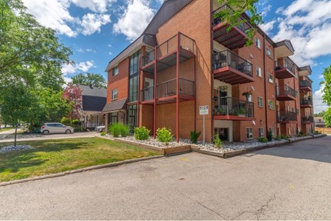 A large red brick apartment building with a parking lot in front.