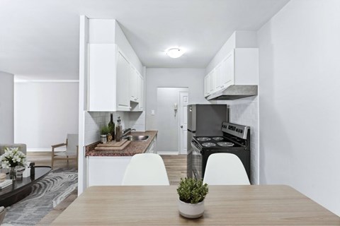 A modern kitchen with a wooden table and white chairs.
