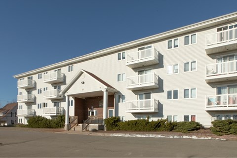 A large white apartment building with balconies and a covered entrance.