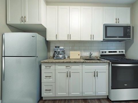 A kitchen with a refrigerator, microwave, oven, and cabinets.
