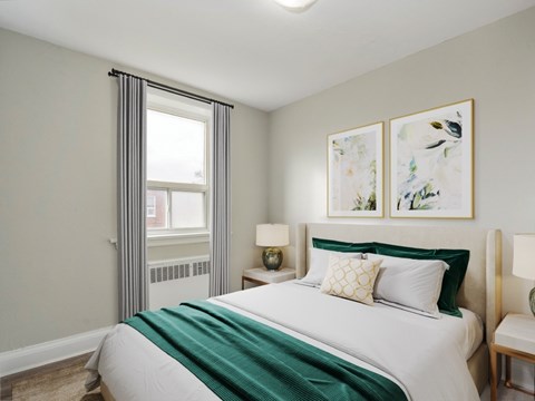 A bedroom with a large bed and two framed pictures on the wall.