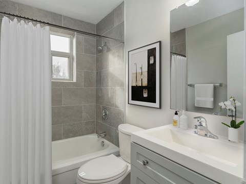 A bathroom with a white toilet, a white sink, and a shower with a white curtain.