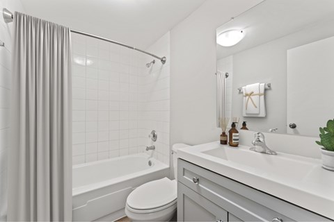 A white bathroom with a toilet, sink, and shower.
