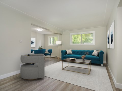 A living room with a blue couch and a grey ottoman.