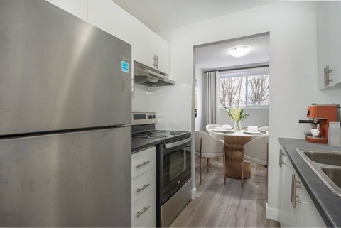 A modern kitchen with a stainless steel refrigerator and a dining table set for two.