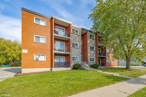 A red brick apartment building with a balcony on the second floor.