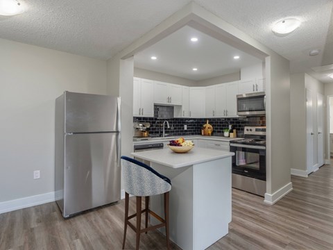 A kitchen with a refrigerator, island, and stove.