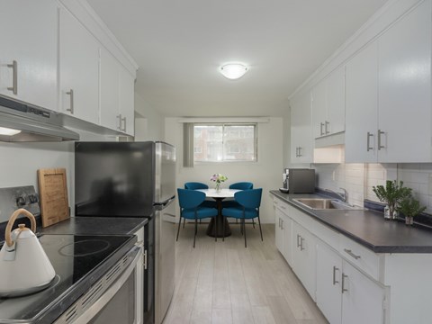 A kitchen with white cabinets and a black refrigerator.
