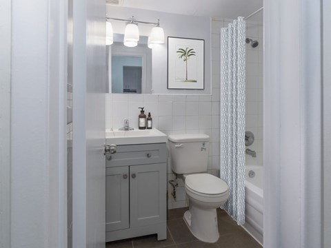 A white toilet sits in a bathroom next to a sink and a shower curtain.