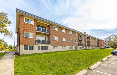 A red brick apartment building with a green lawn in front.