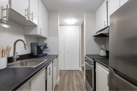 A modern kitchen with white cabinets and stainless steel appliances.