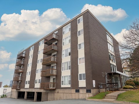 A large apartment building with a brown and beige exterior and balconies on the second floor.