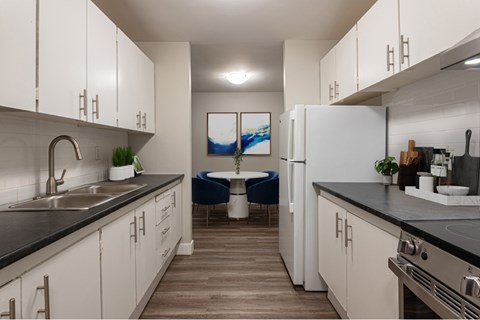 A modern kitchen with white cabinets and a black countertop.