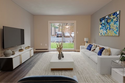 A living room with a white couch, a television, and a painting on the wall.