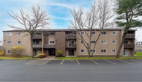 A large apartment complex with a parking lot in front.