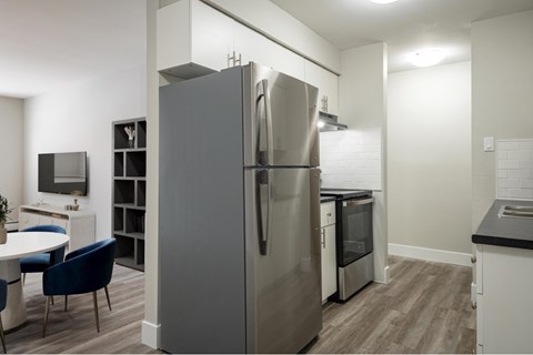 A modern kitchen with a large refrigerator and a dining table with chairs.