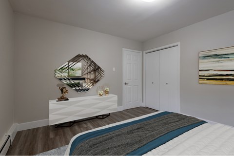 A bedroom with a bed, a mirror, and a painting on the wall.