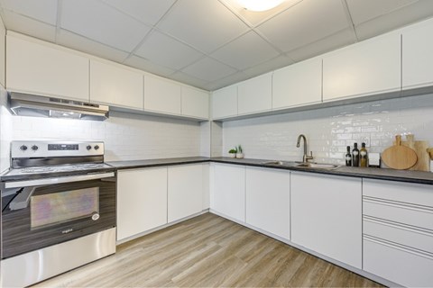 A modern kitchen with a stove and white cabinets.
