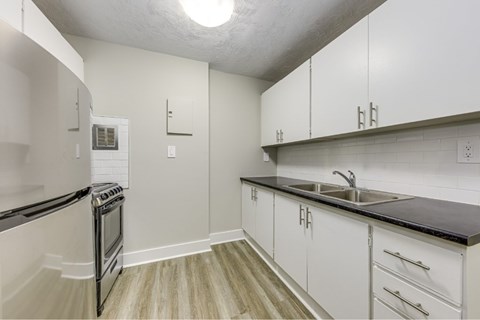 A kitchen with white cabinets and a black counter top.
