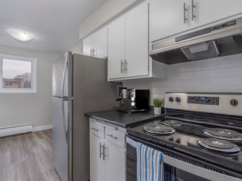 A modern kitchen with a stainless steel stove and white cabinets.
