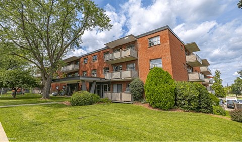 A red brick apartment building with a green lawn in front.