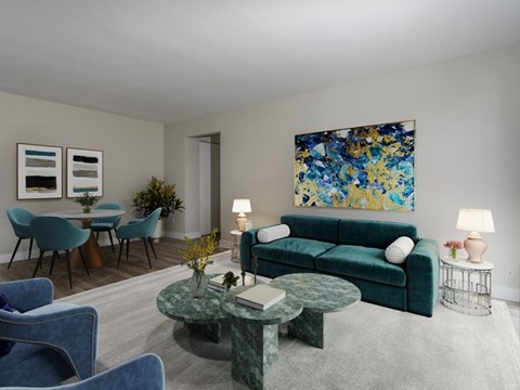 A living room with a green couch and a painting on the wall.