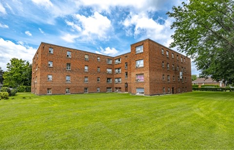 A large red brick building with a green lawn in front.
