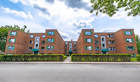 A large red brick building with green awnings and windows.