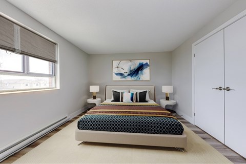 A bedroom with a bed, two lamps, and a painting on the wall.