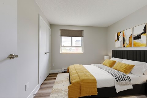 A bedroom with a bed, yellow pillows, and a window.