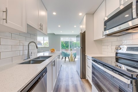 A modern kitchen with white cabinets and stainless steel appliances.
