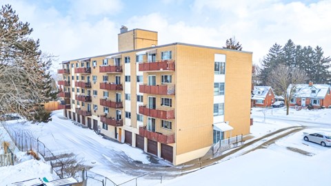 A large apartment building with a snowy landscape in front.