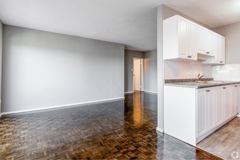A kitchen with white cabinets and a wooden floor.