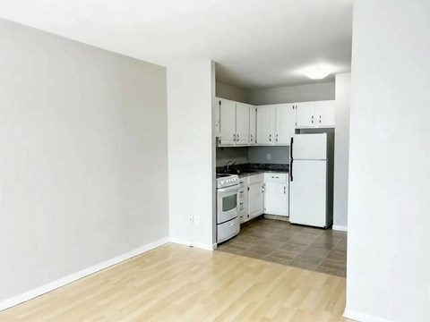 A kitchen with white appliances and wooden floors.