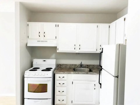 A white kitchen with a stove, sink, and refrigerator.