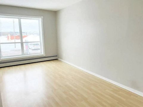A room with a large window and wooden flooring.