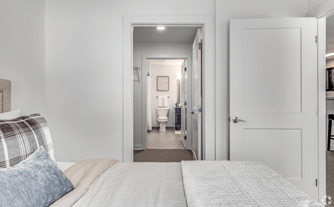 A bedroom with a bed and a mirror in the hallway.