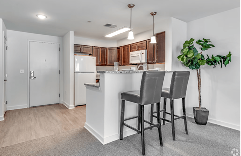 A kitchen with a white island and brown chairs.