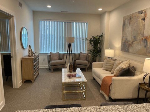 A living room with a white couch, a coffee table, and a large painting on the wall.