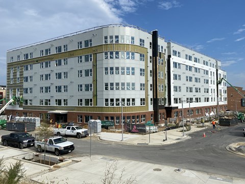 A large white building with a green roof is under construction.