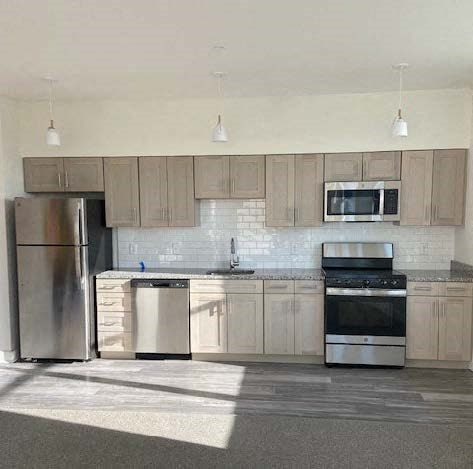 A kitchen with a refrigerator, microwave, oven, and sink.