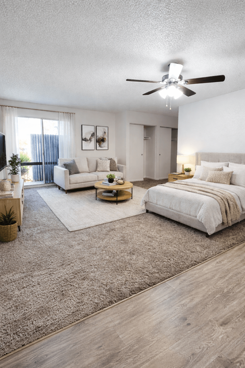 A well-lit bedroom with a large bed and a living area with a couch and a coffee table.