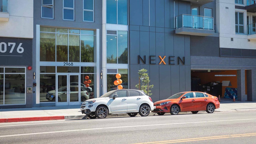 Two cars are parked in front of a building with the sign "NEXEN".