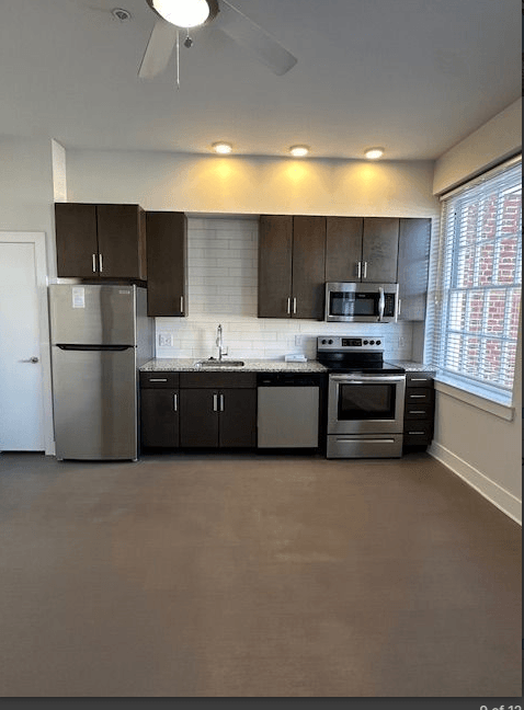 A kitchen with a refrigerator, microwave, oven, and sink.