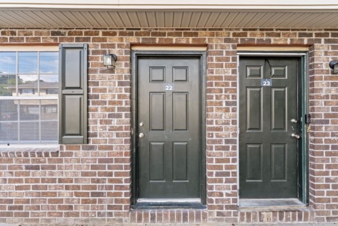 A brown brick wall with three doors.
