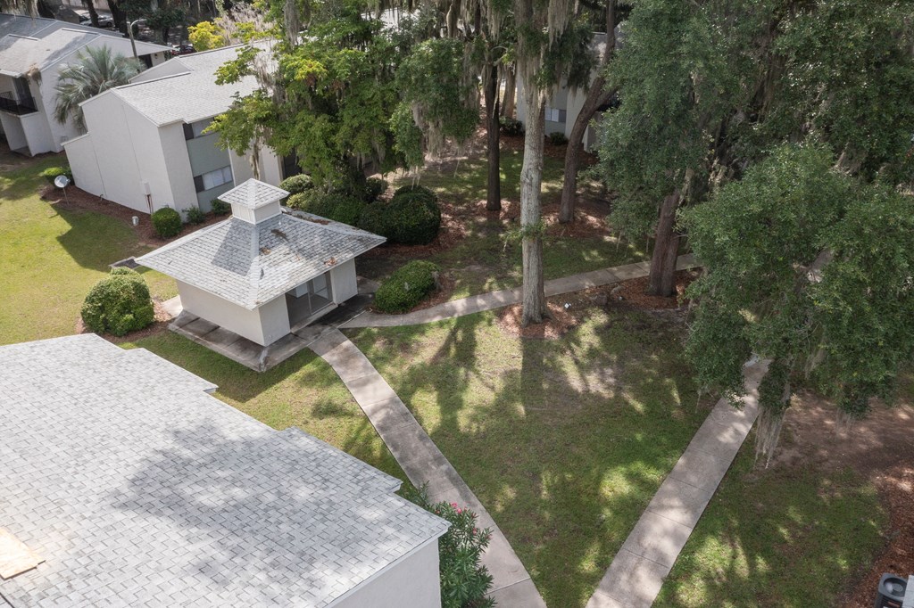 A white house with a grey roof and a small tower-like structure in the front yard.
