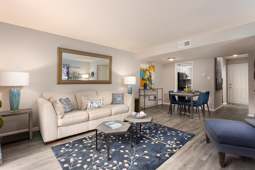 A living room with a white couch, a coffee table, and a mirror on the wall.