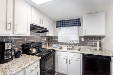 A kitchen with white cabinets and a black stove top.